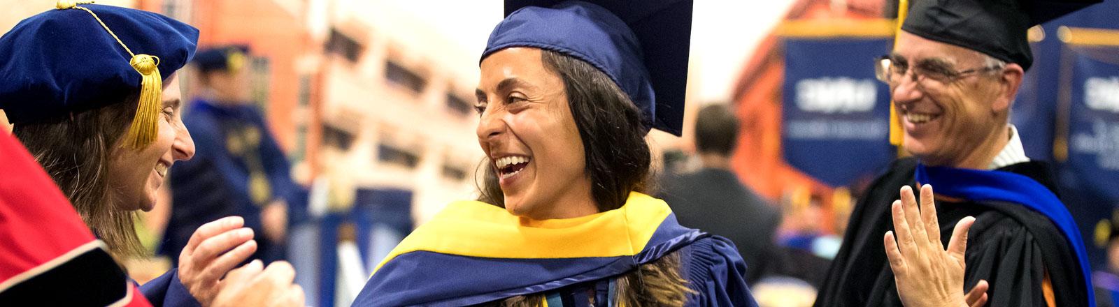 Female graduate student receiving congratulations at commencement ceremony.